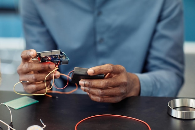 Gros Plan D'un Jeune Homme Noir Tenant Une Carte De Circuit Imprimé Tout En Construisant Un Espace De Copie De Robot