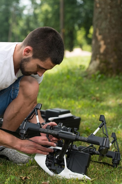 Gros plan d'un jeune ingénieur vérifiant la caméra d'un drone avec la main dans le parc