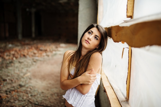 Gros plan d'une jeune jolie fille brune posée sur un lieu abandonné.