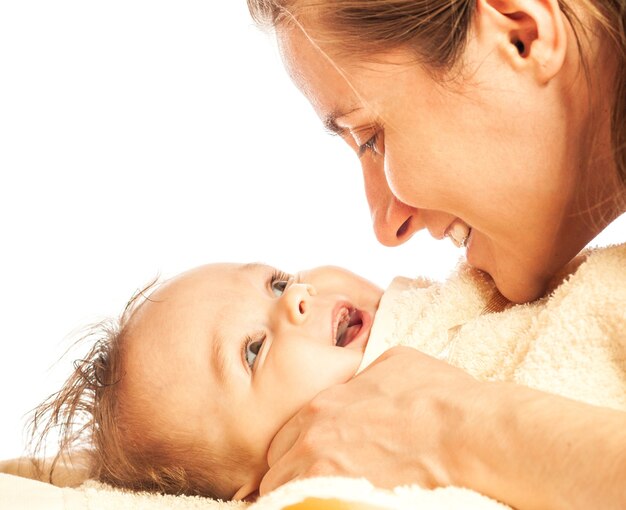 Gros plan, une jeune mère attentionnée essuie une petite fille mignonne d'un demi-an après s'être baignée sur un fond blanc. Place pour la publicité des produits pour bébés. Espace de copie