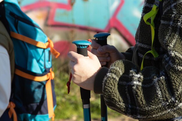 Gros plan sur une jeune routarde marchant avec des bâtons de randonnée. Femme portant un pull chaud en randonnée à l'extérieur. Concept de week-end en plein air