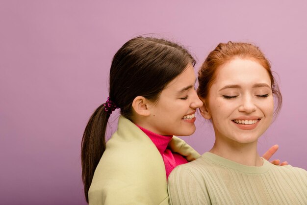 Gros plan de jeunes femmes à la peau claire rousse et brune souriante avec les yeux fermés sur fond violet Style de vie différentes émotions concept de loisirs