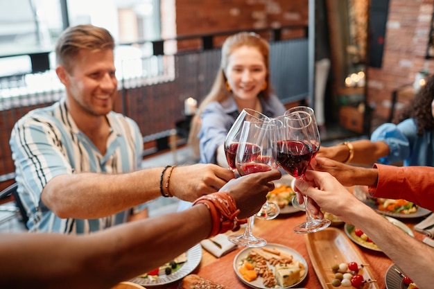 Gros plan de jeunes portant un toast avec des verres à vin tout en célébrant le dîner ensemble copie savs