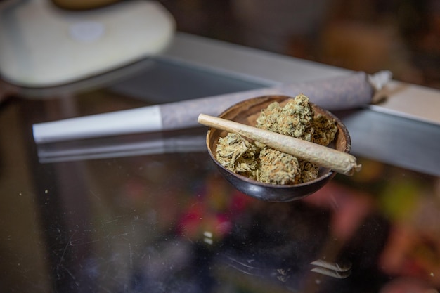 Photo gros plan d'un joint roulé avec de la marijuana placé sur de la marijuana brute
