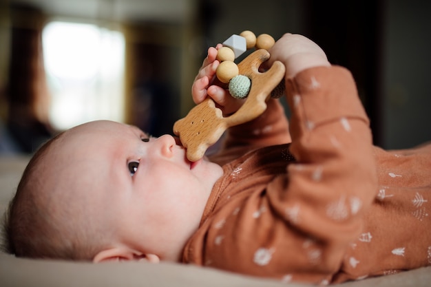 Gros plan Joli bébé sucer jouet sur lit Adorable bébé en pyjama sucer jouet tout en se reposant sur le lit à la maison