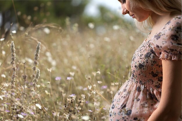 Gros plan d'une jolie femme enceinte avec le ventre sur la prairie d'été