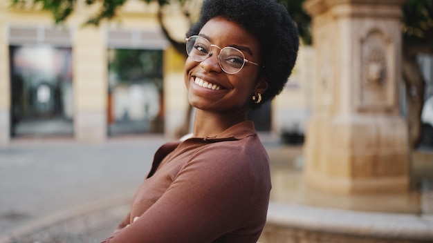 Photo gros plan jolie fille africaine dans des verres souriant sincèrement à la cam