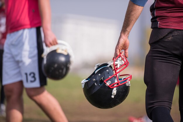 gros plan d'un joueur de football américain tenant un casque noir sur le terrain