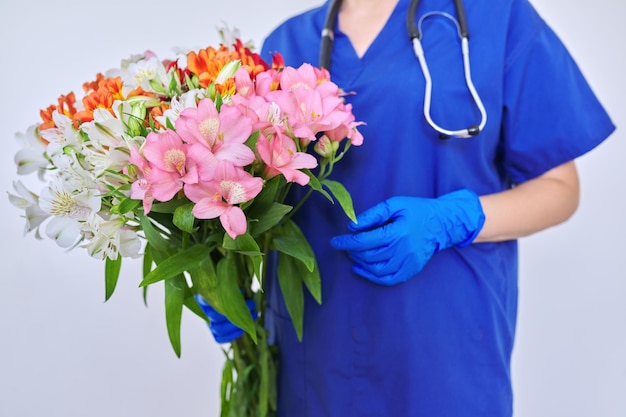 Gros plan de la journée de la santé bouquet de fleurs dans les mains d'une infirmière médecin