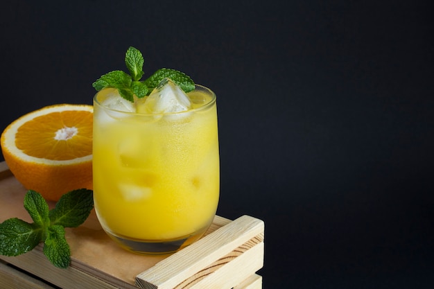 Gros plan sur le jus d'orange avec de la glace dans le verre à boire sur fond noir. Espace de copie.