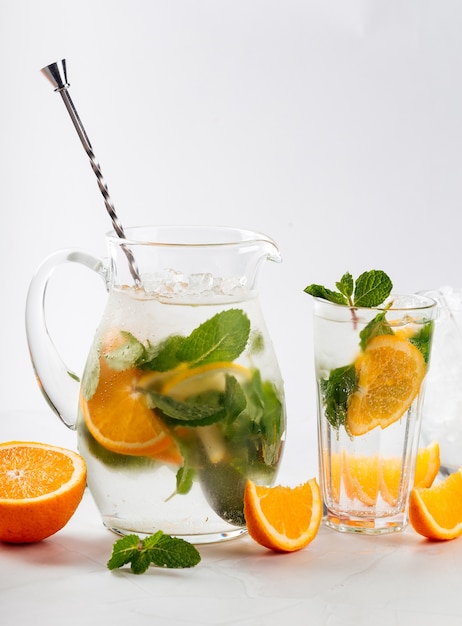 Gros plan sur la limonade orange et menthe dans une cruche et verre isolé