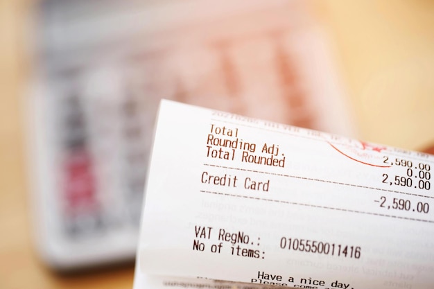 Gros plan de la liste d'épicerie sur papier de réception et de la calculatrice sur la table en bois Calcul du paiement des coûts