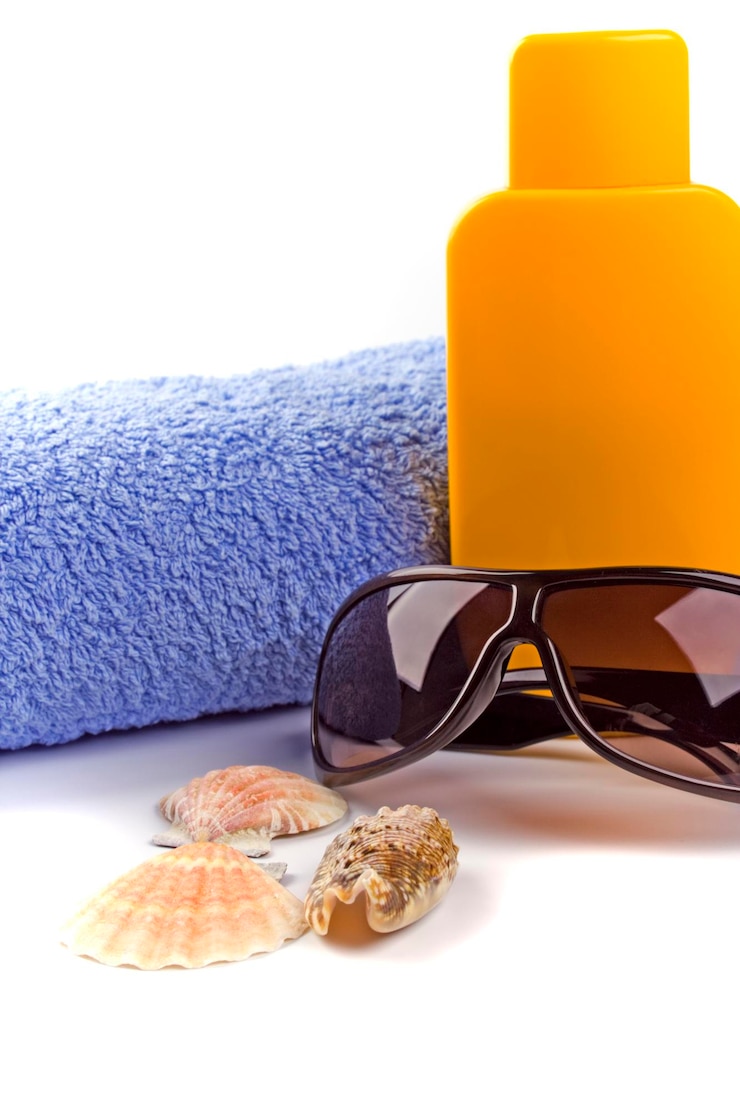 Photo un gros plan de lunettes de soleil avec une bouteille et des coquillages sur fond blanc