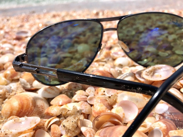 Photo un gros plan de lunettes de soleil sur des coquillages sur la plage.