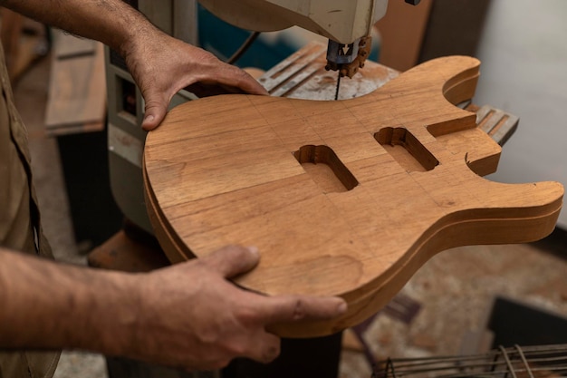 Photo gros plan d'un luthier latino-américain méconnaissable faisant une guitare électrique avec une scie concept de construction d'instruments à cordes