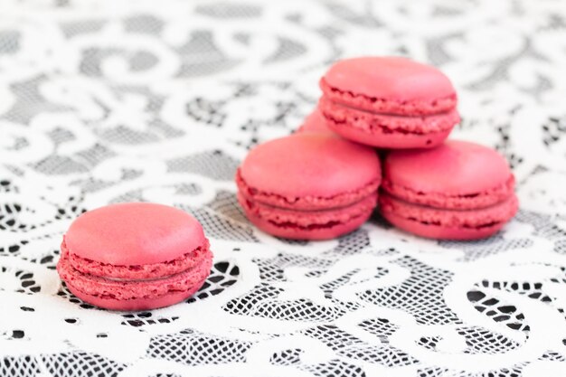 Gros plan de macarons rouges sur fond de dentelle blanche