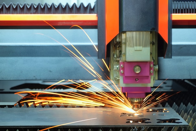 Gros plan, une machine de découpe laser travaille avec une plaque d'acier jusqu'à ce qu'elle fasse des étincelles sur une usine intelligente