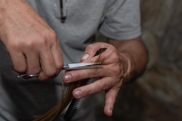 Gros plan main de coiffeur avec des ciseaux sur le lieu de travail Coiffeur prenant les cheveux de la femme pour la coupe Concept de service de salon de beauté