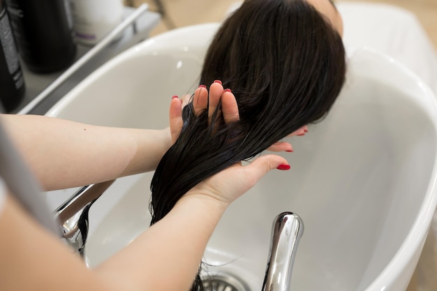 Gros plan de la main d'un coiffeur qui frotte de l'huile hydratante dans les cheveux des clients