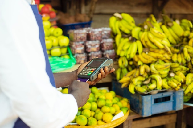 Gros plan sur la main d'un commerçant africain de sexe masculin payant avec une machine terminale