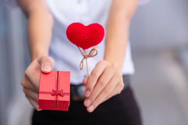 Gros plan main donnant coeur d'amour et boîte-cadeau pour le cadeau de la Saint-Valentin
