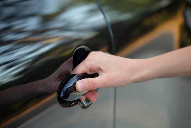 Gros plan de la main du conducteur ouvrant la porte avant de la voiture