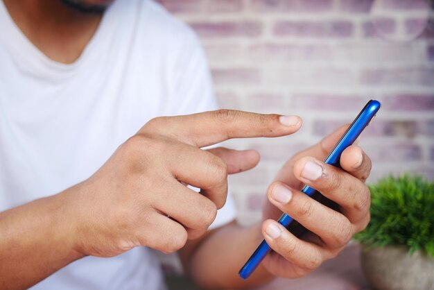 Photo gros plan de la main du jeune homme à l'aide d'un téléphone intelligent