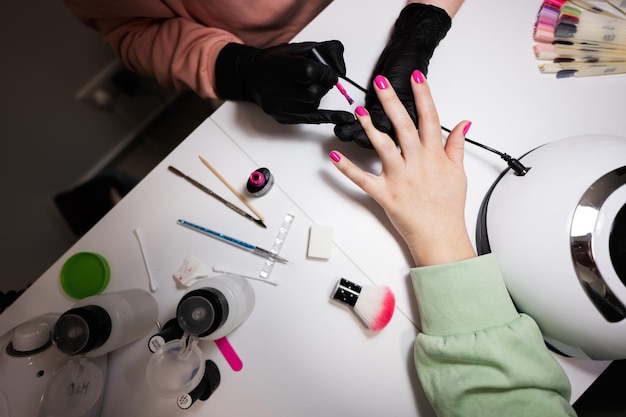 Gros plan de la main du maître manucure travaillant avec une cliente dans un salon de beauté