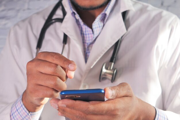 Gros plan de la main du médecin à l'aide de smartphone à l'hôpital.