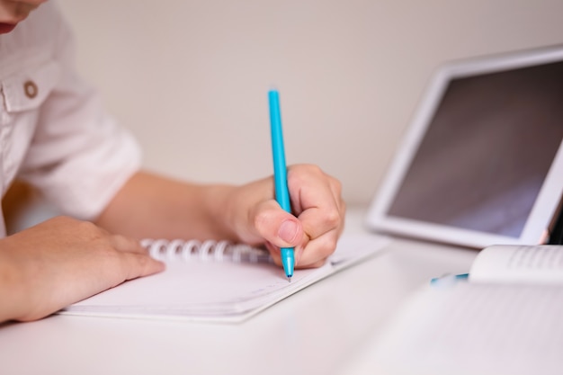 Photo gros plan de la main de l'enfant à prendre des notes dans le pavé d'écriture