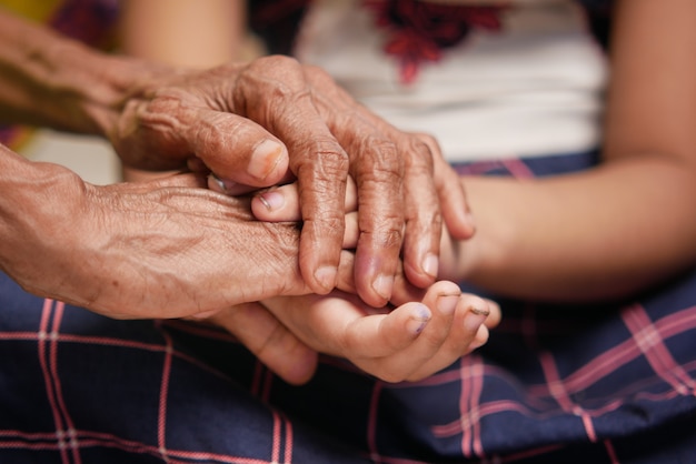 Gros plan de la main de l'enfant tenant la main des femmes âgées