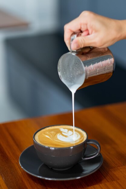 Gros plan main faisant du café d'art latte chaud