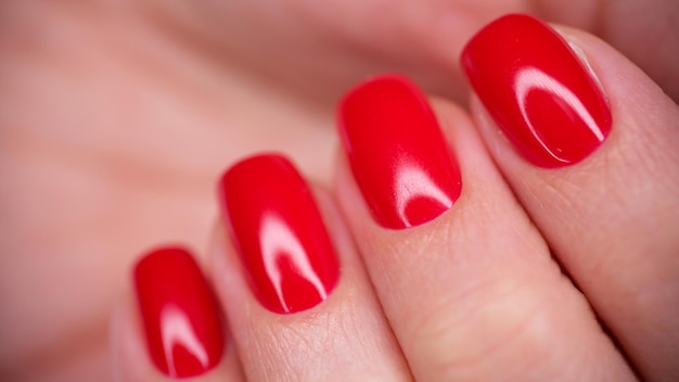 Gros plan d'une main féminine avec du vernis gel rouge vif belle femme avec des ongles parfaits