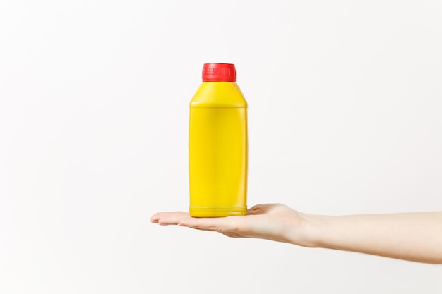 Gros plan sur une main féminine horizontale tient une bouteille vierge vide jaune avec un espace de copie isolé sur fond blanc. Instruments pour la salle d'appartement de rénovation. Réparer le concept de maison. Espace publicitaire.