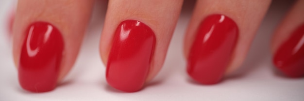 Gros plan d'une main féminine avec une manucure brillante rouge parfaite ongles de belle femme avec du gel