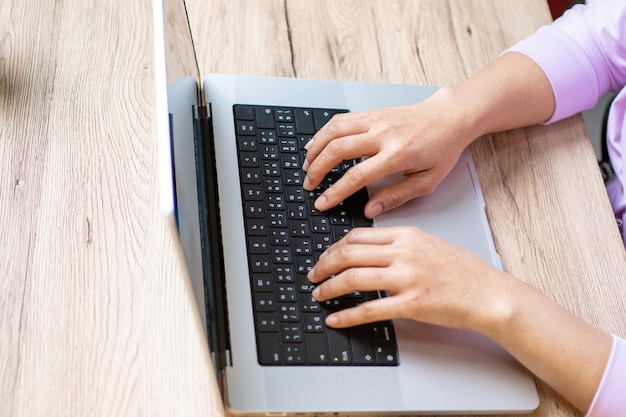 Gros plan main d'une femme d'affaires tapant clavier ordinateur portable sur le bureau de bureau