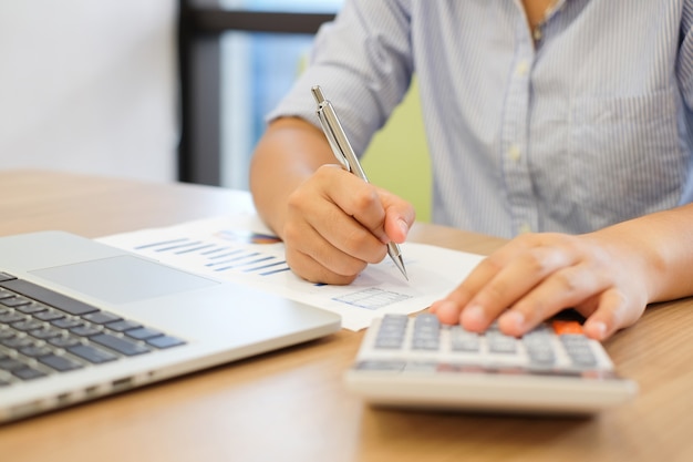 gros plan sur la main de la femme en appuyant sur la calculatrice pour calculer l&#39;estimation des coûts