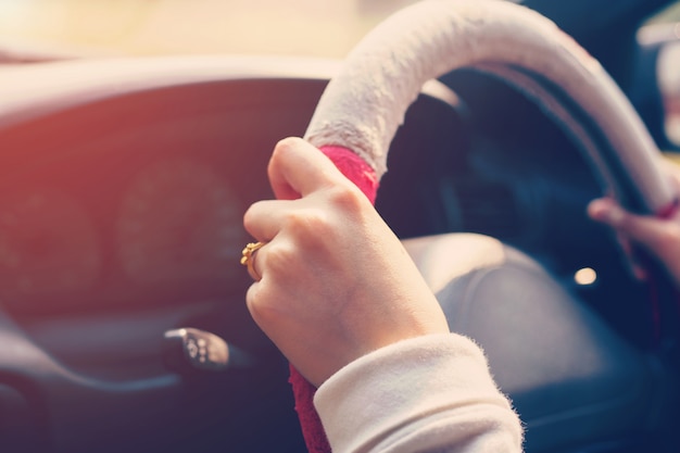 gros plan main femme au volant de voiture sur route avec ton vintage.