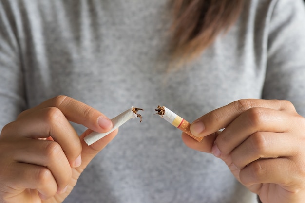 Gros plan d&#39;une main de femme brisant, écrasant ou détruisant des cigarettes