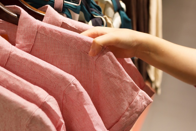 Gros plan de la main de femme choisissant un T-shirt.