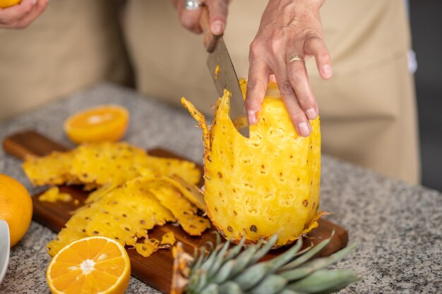 Gros plan de la main de la femme coupant un ananas