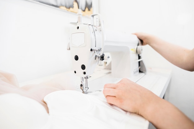 Photo gros plan d'une main de femme designer travaillant sur une machine à coudre