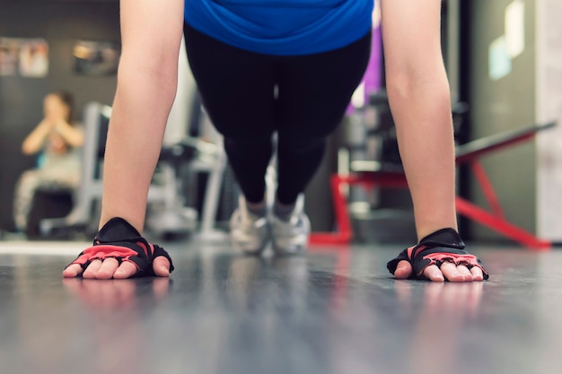 Gros plan sur la main d'une femme faisant des pompes dans la salle de sport. Entraînement des filles dans la salle. Mains gantées sur le sol en gros plan. mitaines.