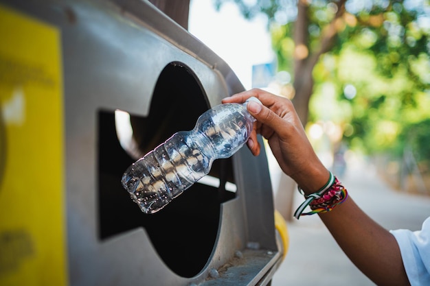 Gros plan d'une main de femme tenant une bouteille en plastique vide pour la jeter à la poubelle