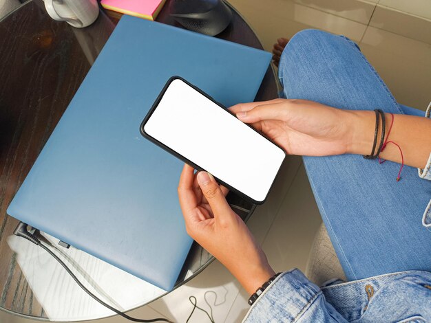 Photo gros plan d'une main de femme tenant un écran blanc de smartphone est une maquette vierge