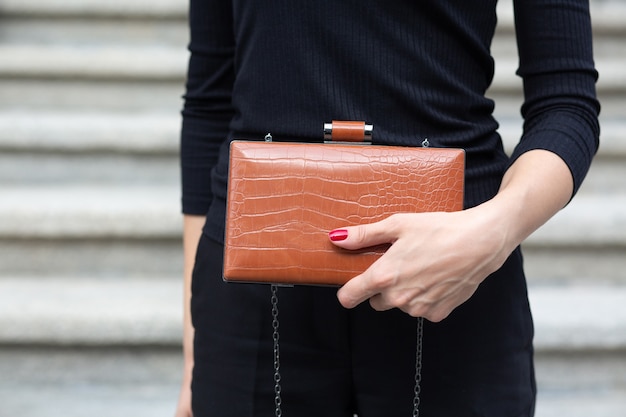 Photo gros plan d'une main de femme tenant un petit sac à main en cuir marron. espace pour le texte