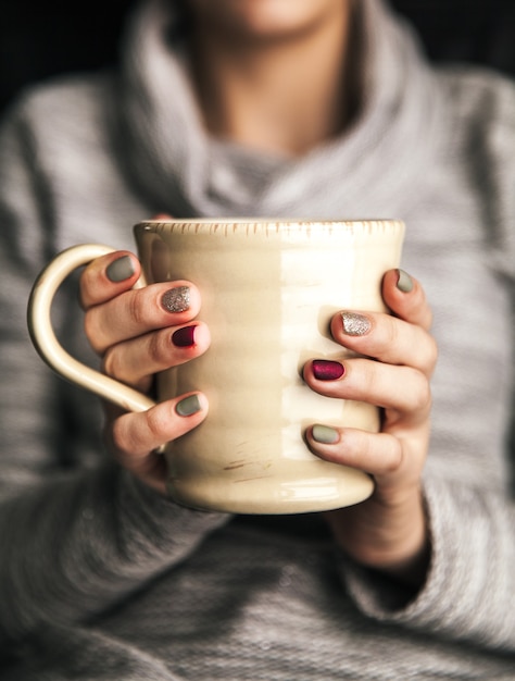 Gros plan d'une main de femme tenant une tasse de café chaud. mode, loisirs