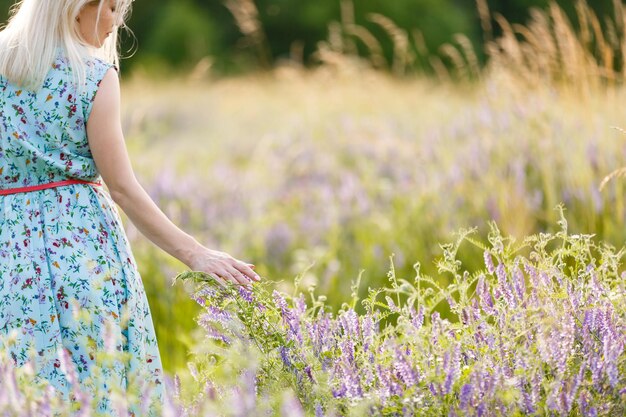 Gros plan de la main d'une femme touchant l'herbe dorée