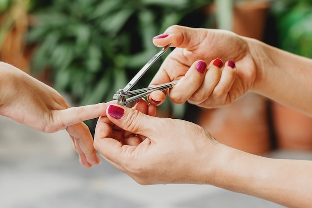 Gros plan La main d'une femme utilise un coupe-ongles pour couper les ongles d'un garçon