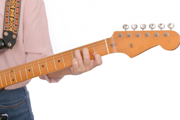 Gros plan de la main de femme avec des vêtements décontractés tenant le cou de la guitare et jouer un accord isolé sur fond blanc